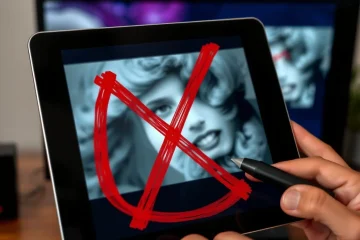 alt_text: A hand draws a red X on a blurry tablet image, while a clear version is displayed on a monitor, symbolizing exclusion and refinement.
